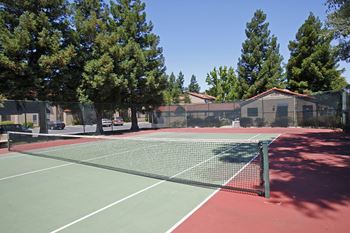 a tennis court with trees and buildings in the background at Valley Plaza Villages, California, 94566